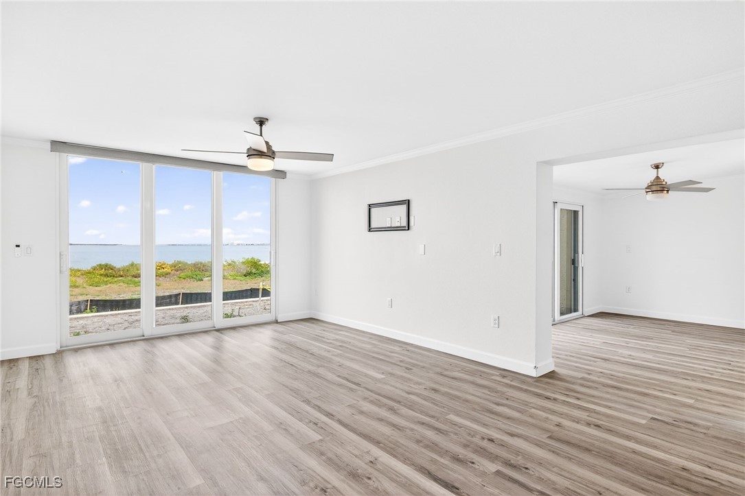 200 Periwinkle Way, Unit 124 Sanibel, FL 33957 - Photo 19 of 50 an empty room with wooden floor ceiling fan and windows