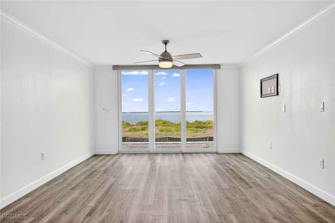 200 Periwinkle Way, Unit 124 Sanibel, FL 33957 - Photo 6 of 50 an empty room with wooden floor chandelier fan and windows