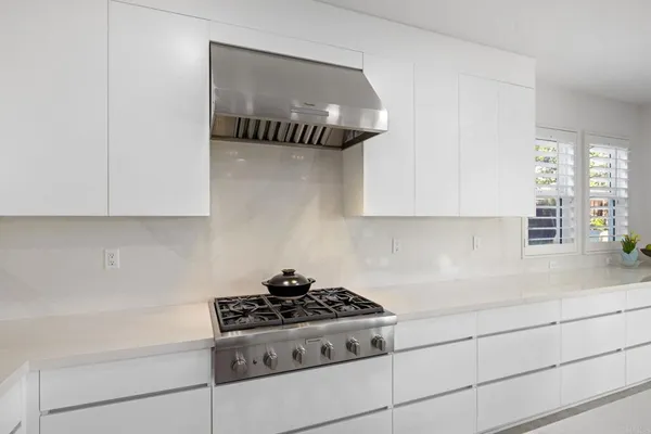 a large white kitchen with stainless steel appliances granite countertop a stove a sink a refrigerator and a refrigerator