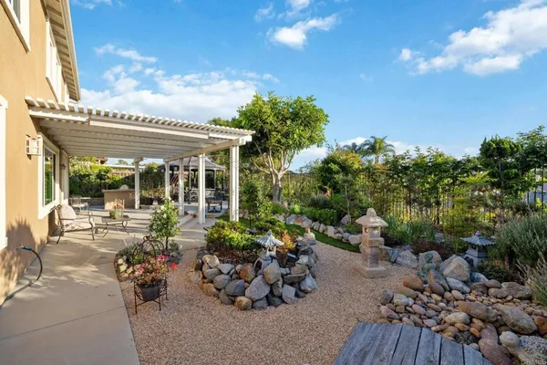 a patio with a table and chairs under an umbrella with a barbeque