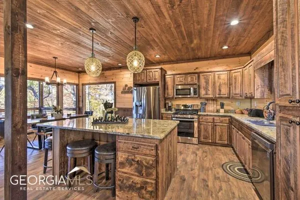 a kitchen with stainless steel appliances granite countertop wooden cabinets a stove a sink and dishwasher a oven with wooden floor