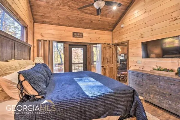 a spacious bedroom with a bed and a flat screen tv