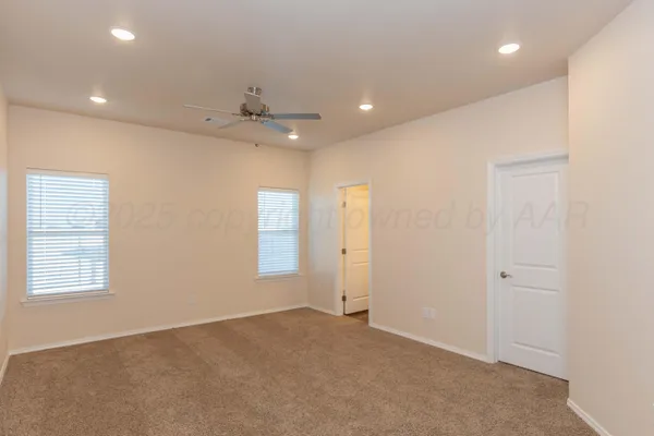 an empty room with windows and ceiling fan