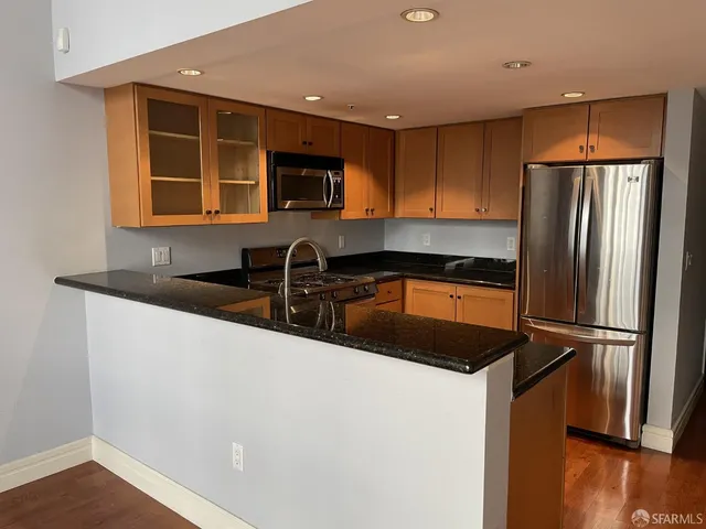 a kitchen with stainless steel appliances granite countertop a refrigerator a sink and a stove