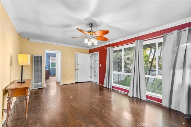 a view of an empty room with wooden floor and a window