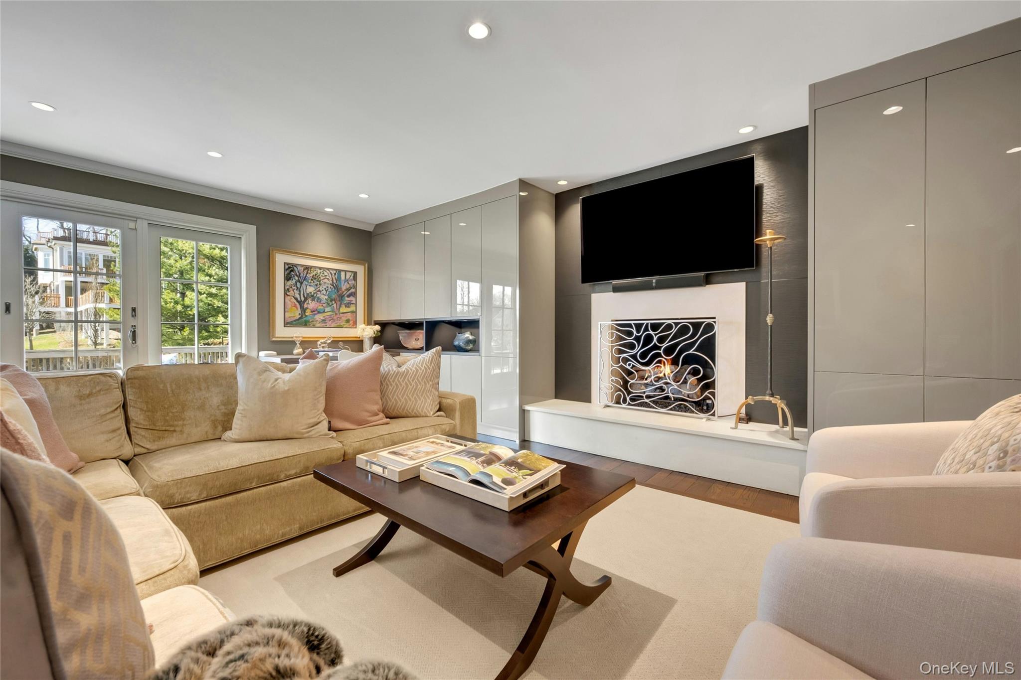 44 Brevoort Lane Rye, NY 10580 - Photo 10 of 32 Sleek custom built-ins by Georgio frame the gas fireplace, creating a sophisticated family room with walkout to the deck