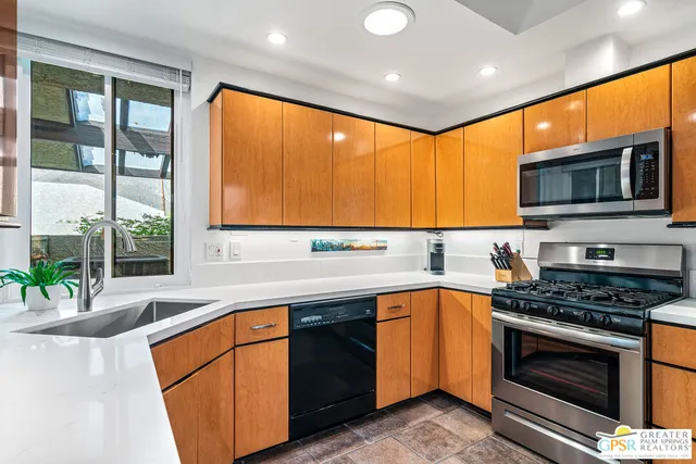 a kitchen with stainless steel appliances granite countertop a refrigerator a stove a sink and a microwave