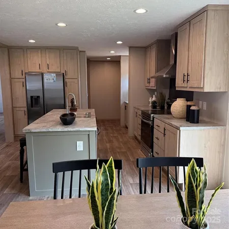 a kitchen with stainless steel appliances granite countertop a refrigerator a stove a sink cabinets and a dining table