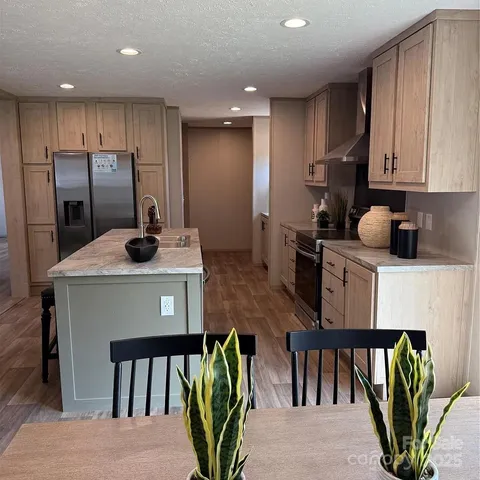 a kitchen with stainless steel appliances granite countertop a refrigerator a stove a sink cabinets and a dining table