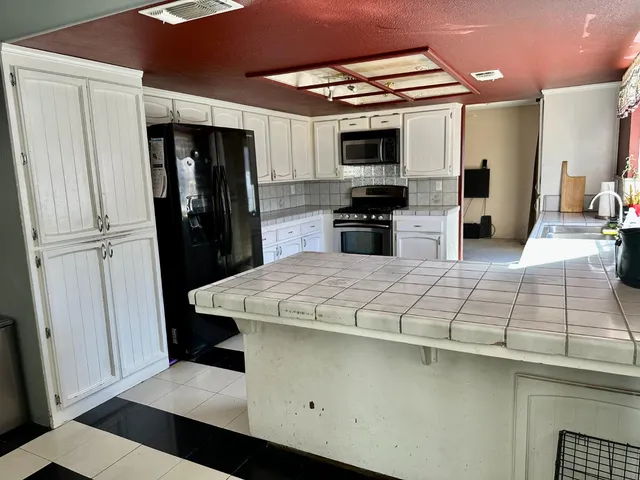 a kitchen with stainless steel appliances kitchen island granite countertop a refrigerator and a sink