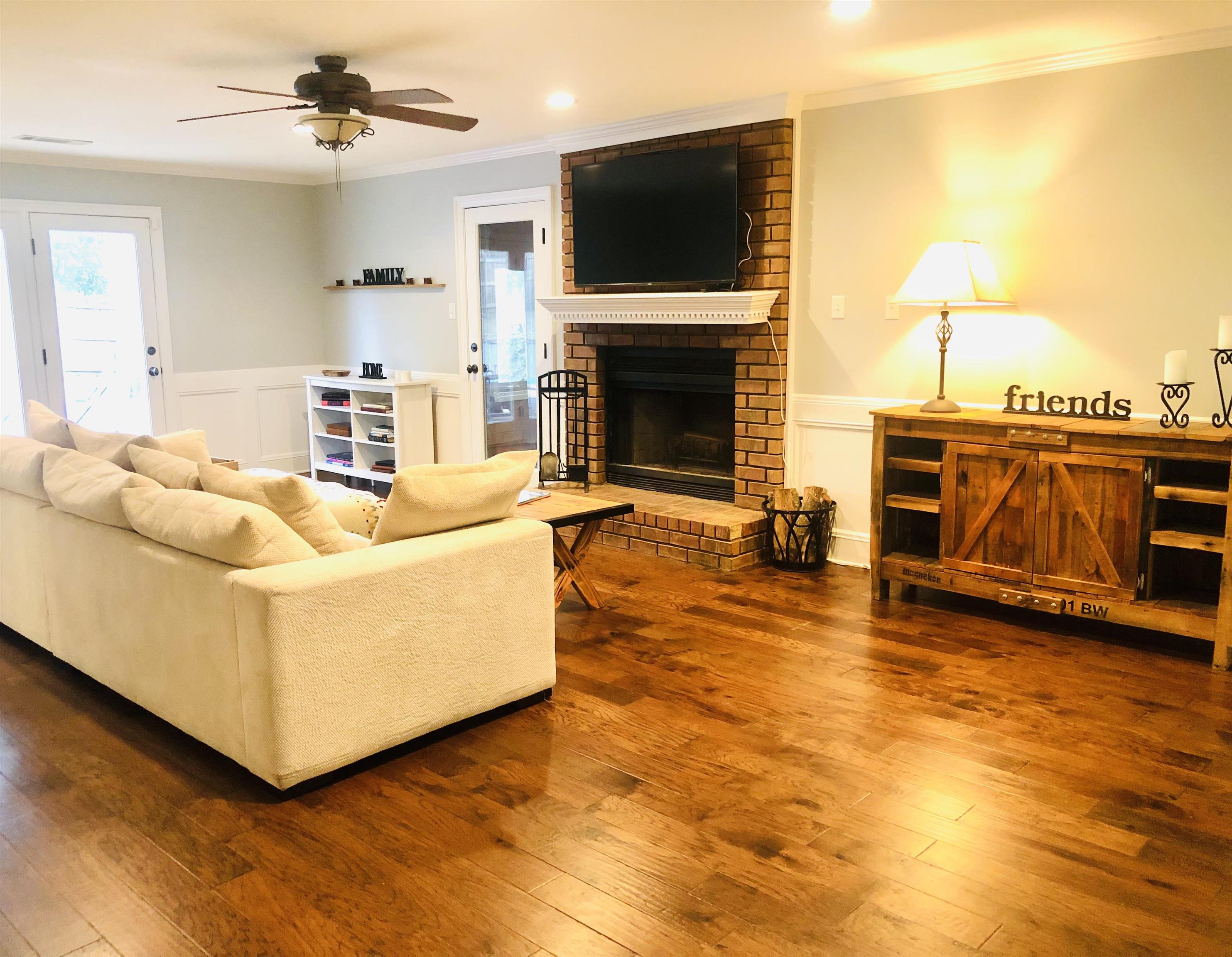 8861 Walnut Ridge Loop Memphis, TN 38018 - Photo 4 of 20 Living room featuring ceiling fan, brick wall, hardwood / wood-style floors, ornamental molding, and a fireplace