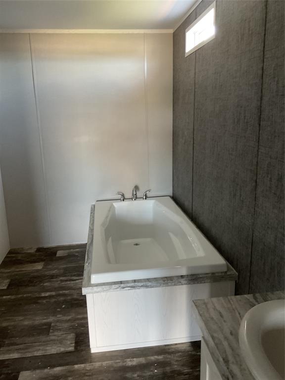 137 Firefly Drive Springtown, TX 76082 - Photo 6 of 12 White soaking tub with chrome fixtures, set against a dark wood-finish flooring