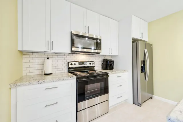 a kitchen with stainless steel appliances white cabinets and a refrigerator