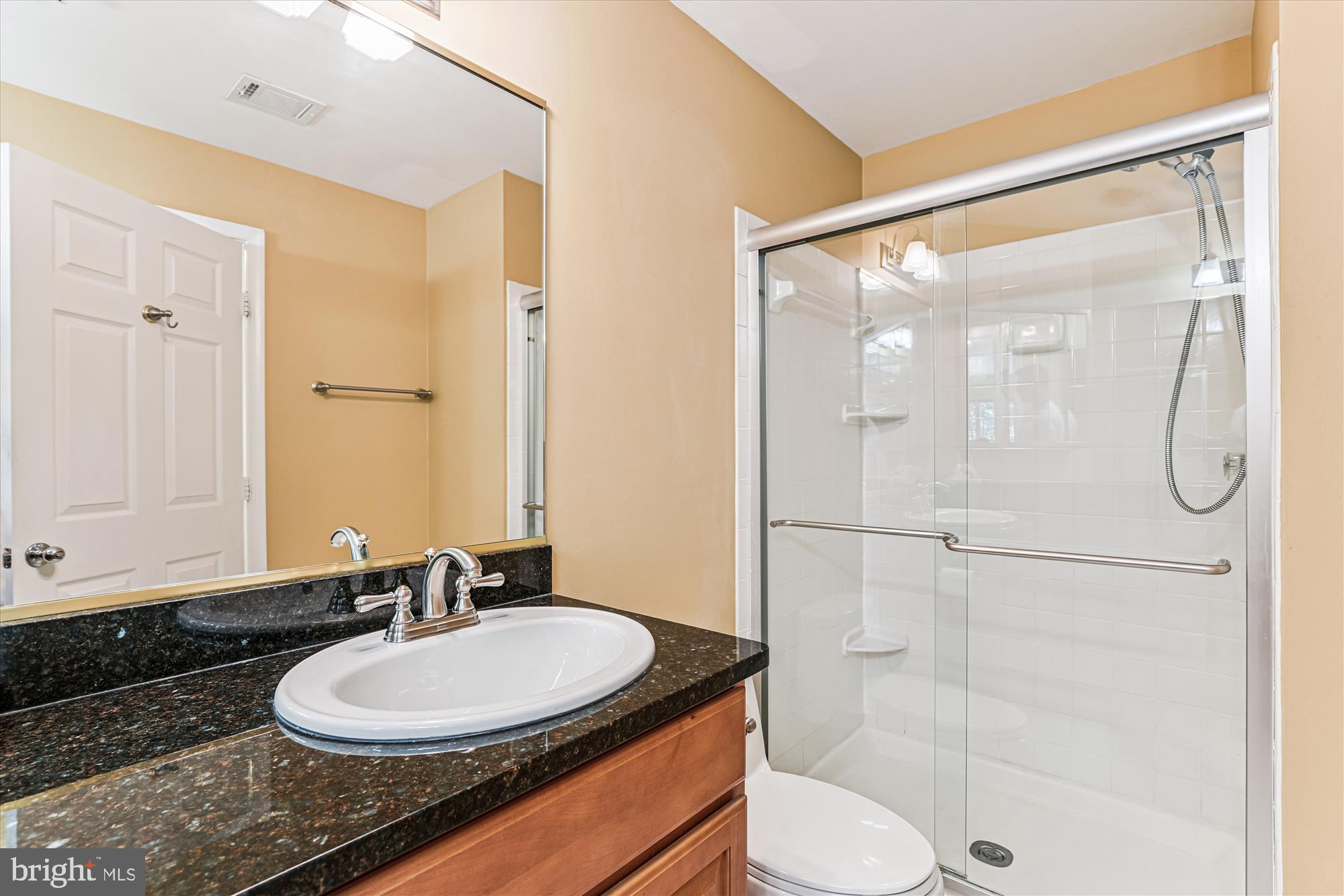 1307 Windleaf Drive, Unit 139N Reston, VA 20194 - Photo 28 of 38 a bathroom with a granite countertop sink toilet a mirror and shower