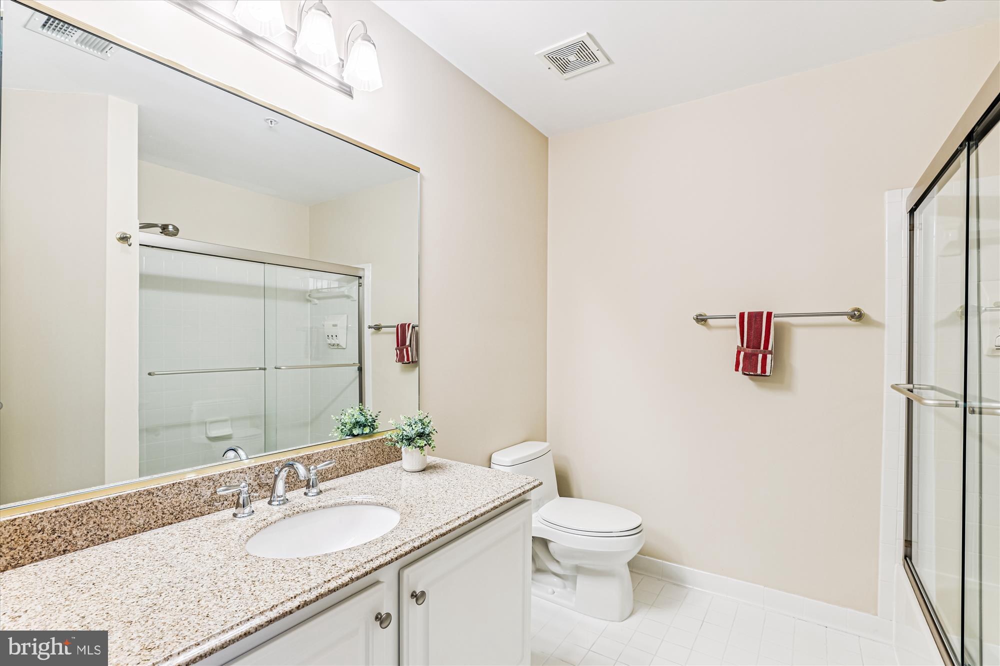 1307 Windleaf Drive, Unit 139N Reston, VA 20194 - Photo 33 of 38 a bathroom with a granite countertop sink toilet and mirror