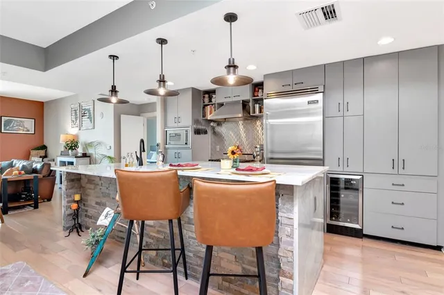 a kitchen with stainless steel appliances kitchen island granite countertop a table chairs and a refrigerator