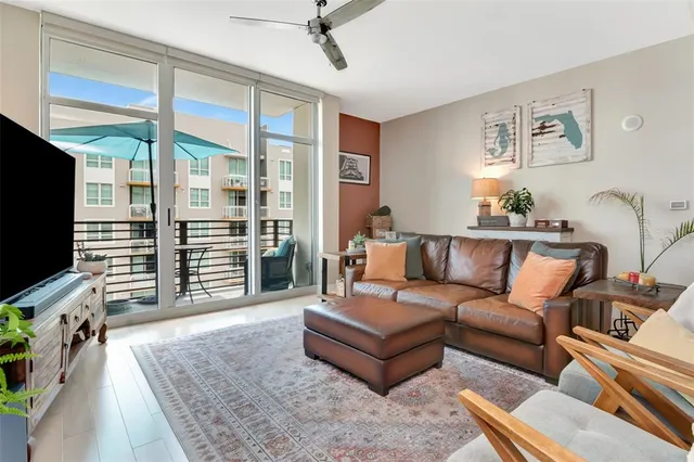 a living room with furniture a flat screen tv and a floor to ceiling window