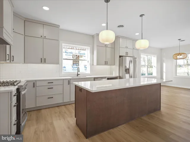 a kitchen with cabinets a sink dishwasher and a stove with wooden floor