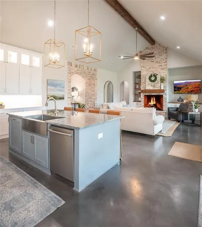 a large white kitchen with a large island oven a stove and a sink with dishwasher
