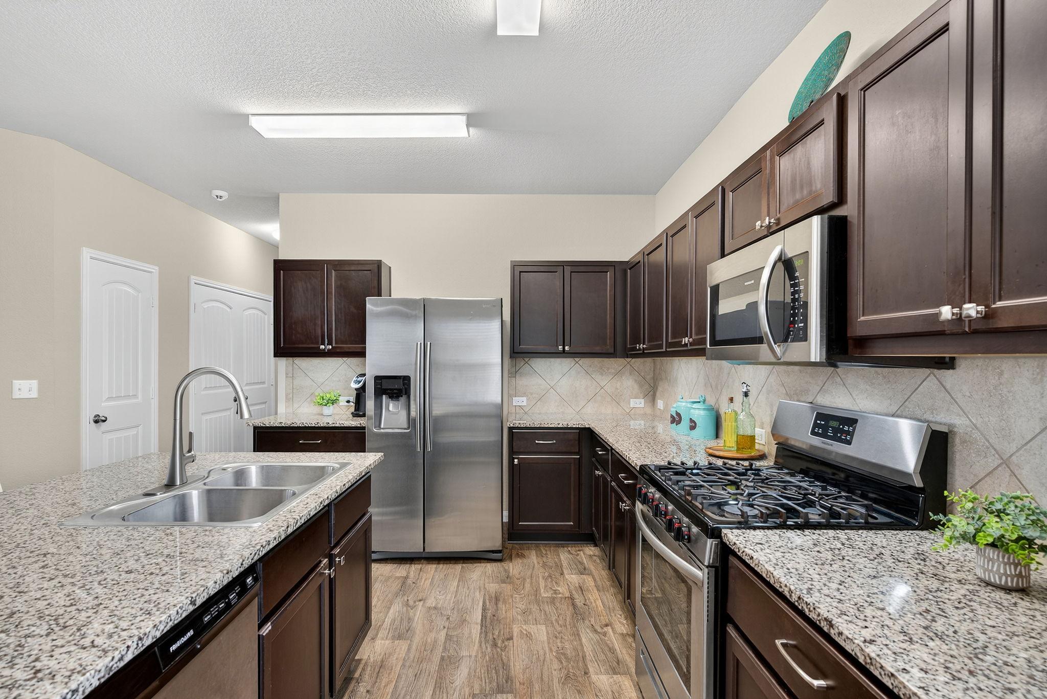 131 Coleto Creek Loop Kyle, TX 78640 - Photo 12 of 30 Kitchen with stainless steel appliances, granite countertops, expresso colored cabinetry, under-cabinet lighting and gas cooking for the home chef.