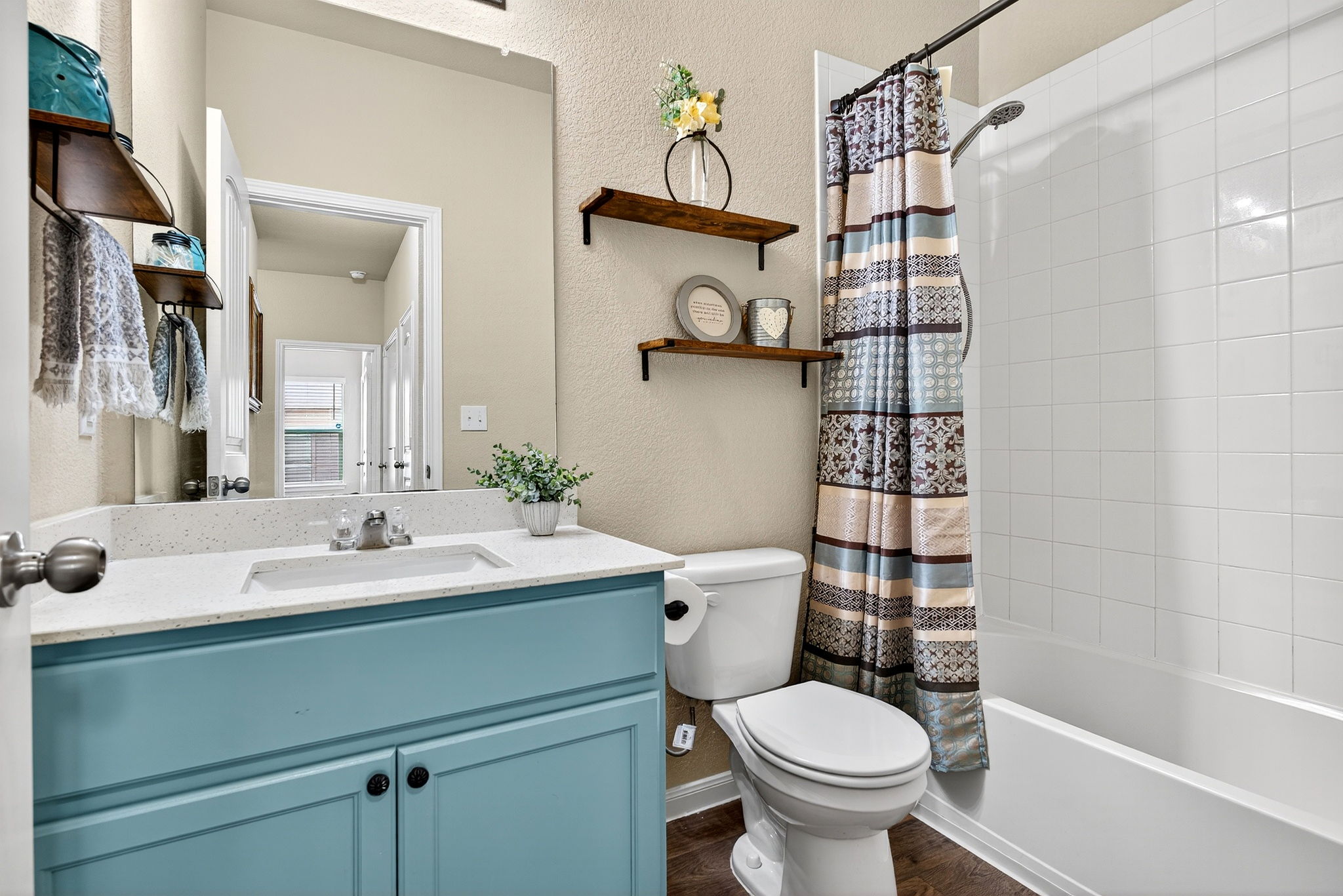 131 Coleto Creek Loop Kyle, TX 78640 - Photo 19 of 30 Charming full guest bath with bright quartz counters, custom open shelving, and a cheerful pop of color.