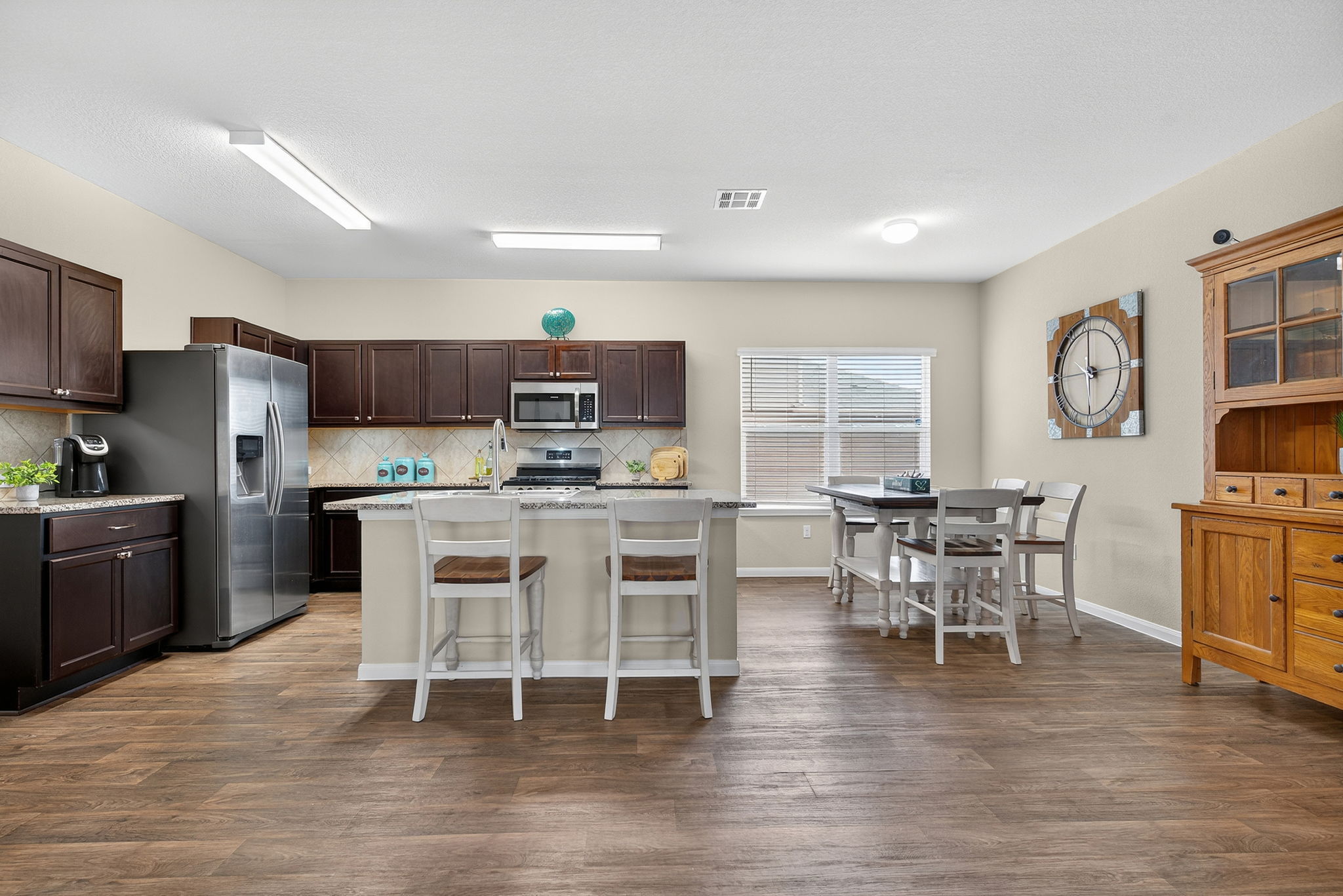 131 Coleto Creek Loop Kyle, TX 78640 - Photo 8 of 30 Spacious kitchen and dining combo with espresso cabinetry, granite countertops, kitchen island and vinyl flooring—perfect for casual mornings or dinner with friends. Refrigerator stays!