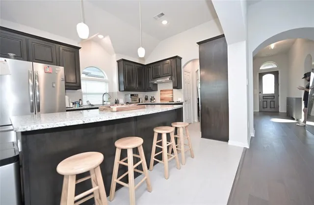 a kitchen with stainless steel appliances granite countertop a refrigerator a stove a sink dishwasher a dining table and chairs with wooden floor