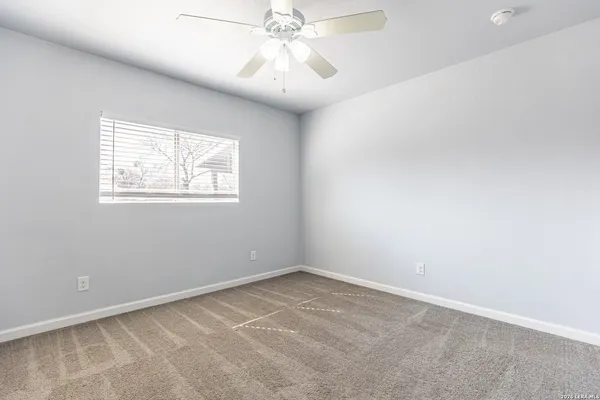 an empty room with windows and fan
