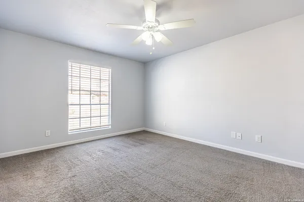 an empty room with windows and chandelier fan