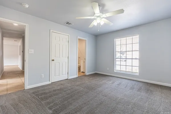 an empty room with windows and fan