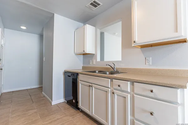 a kitchen with white cabinets and sink