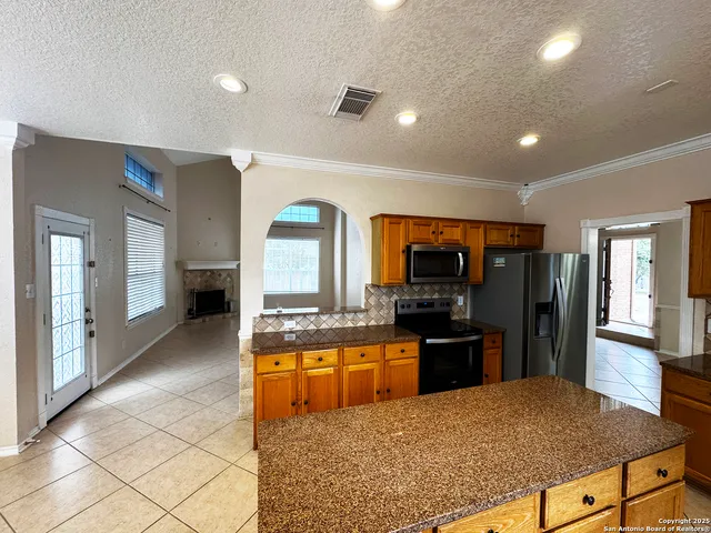 a kitchen with stainless steel appliances granite countertop a stove top oven a sink a dining table and chairs
