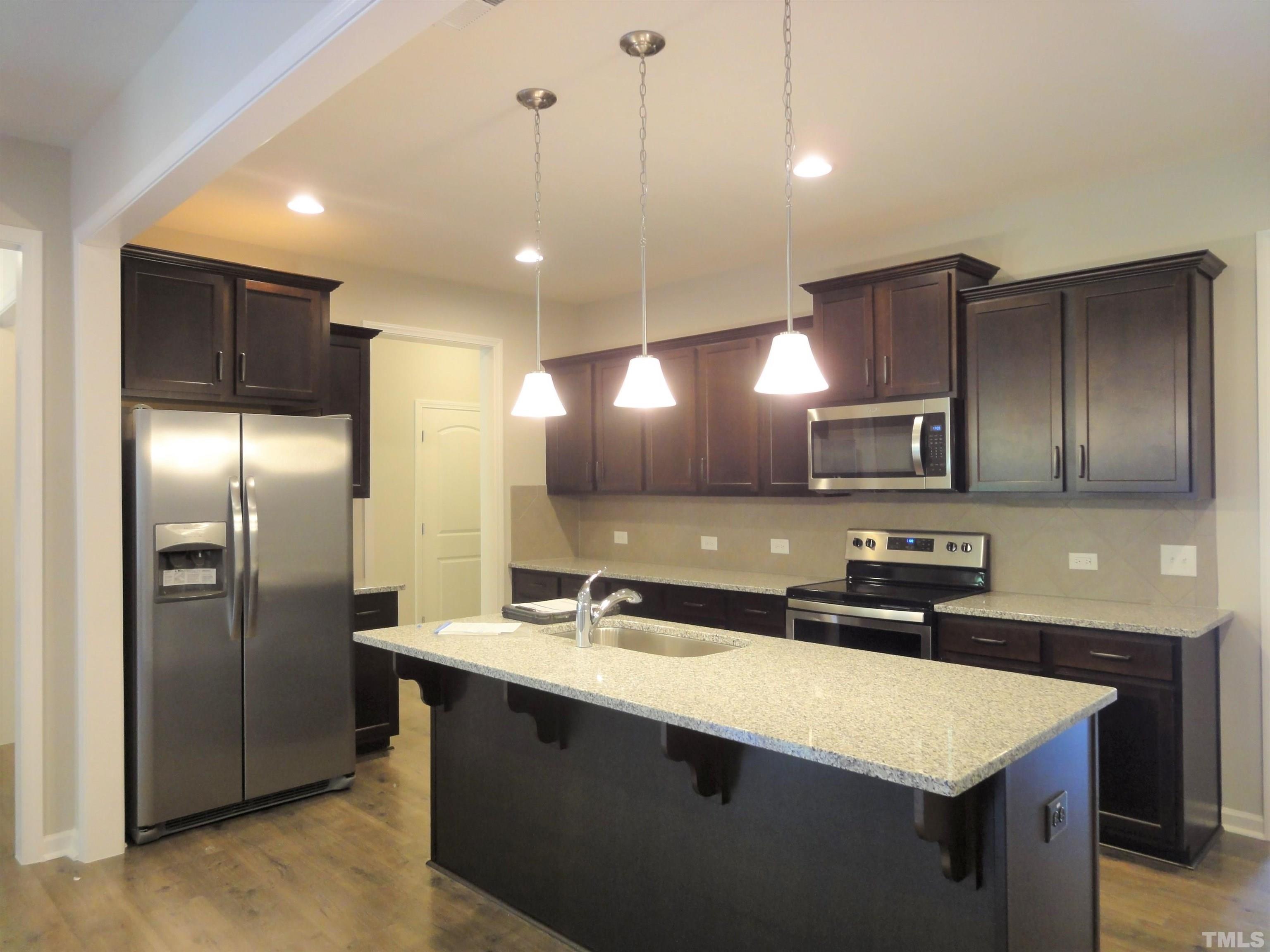 565 Metro Station Apex, NC 27502 - Photo 7 of 29 a kitchen with stainless steel appliances granite countertop a sink a refrigerator and a refrigerator