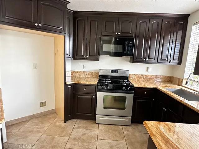 a kitchen with granite countertop wooden cabinets a stove and a sink