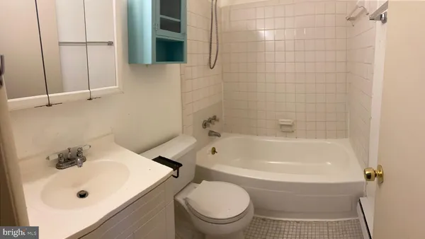 a white bath tub sitting next to a white sink and a toilet