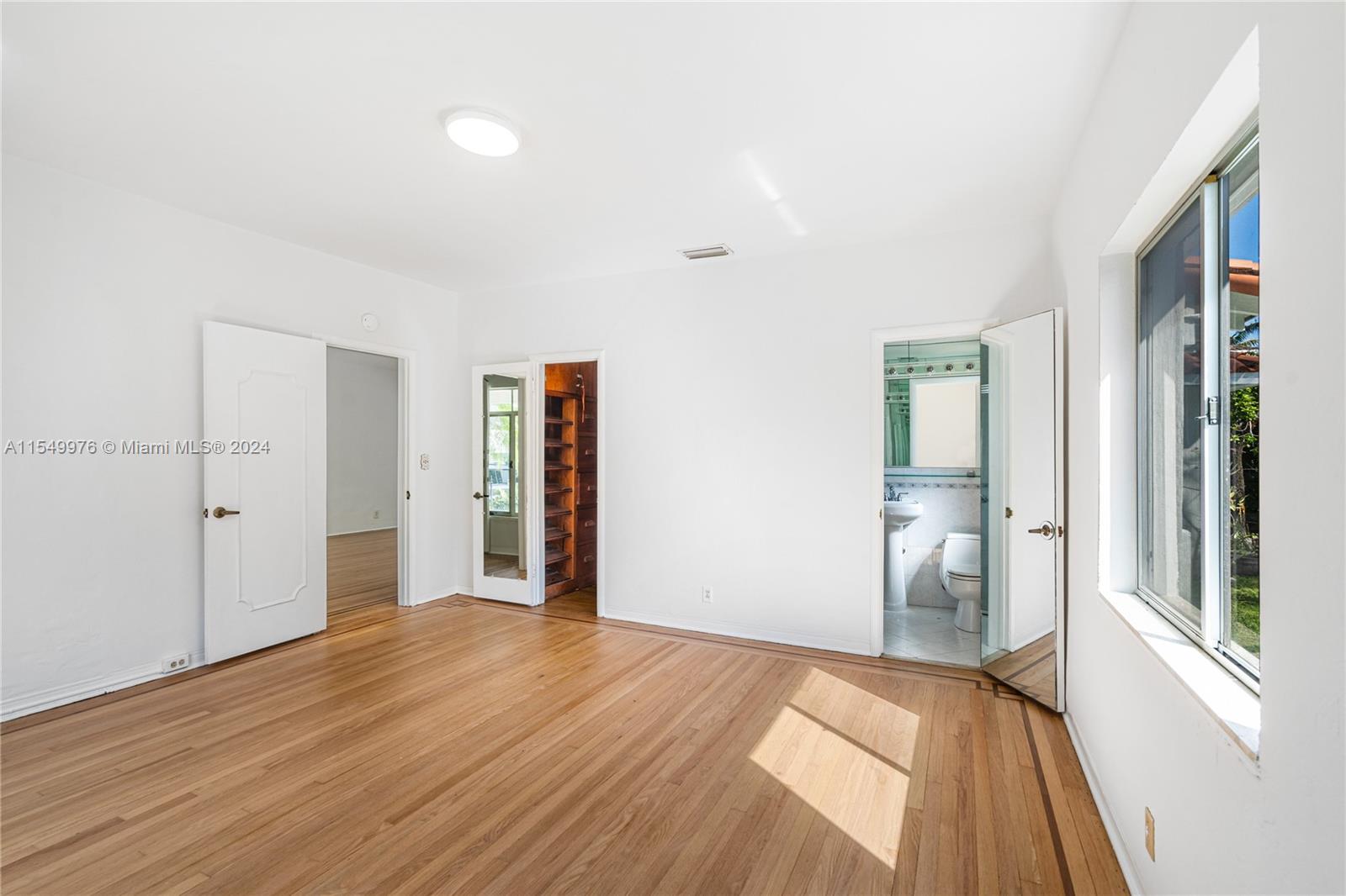 2935 North Bay Road Miami Beach, FL 33140 - Photo 14 of 36 a view of an empty room with wooden floor and a window