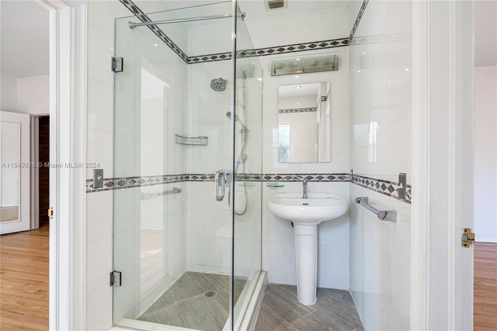 2935 North Bay Road Miami Beach, FL 33140 - Photo 18 of 36 a bathroom with a sink a mirror and a shower