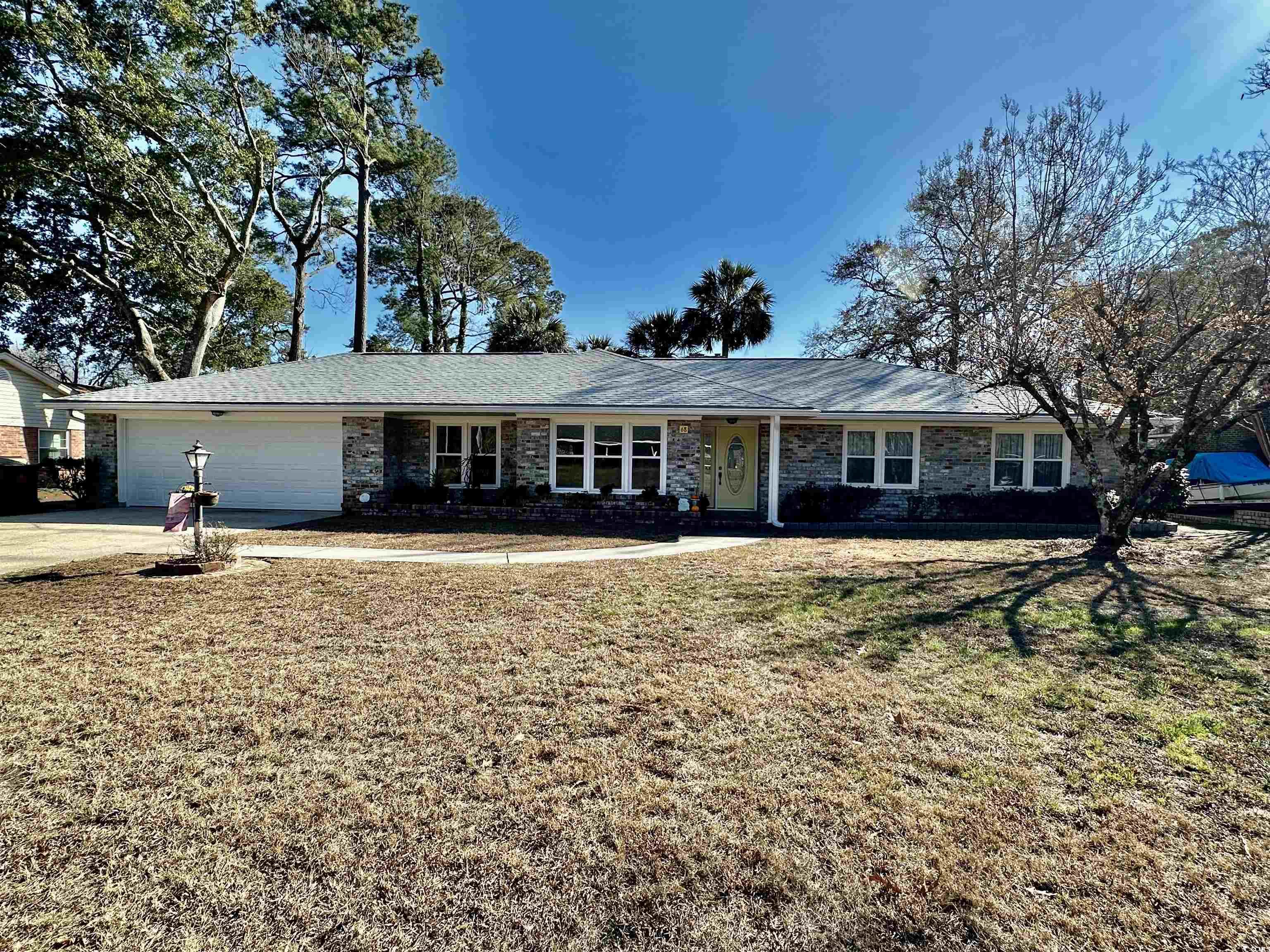 Ranch-style house featuring a front yard, an attached garage, and concrete driveway