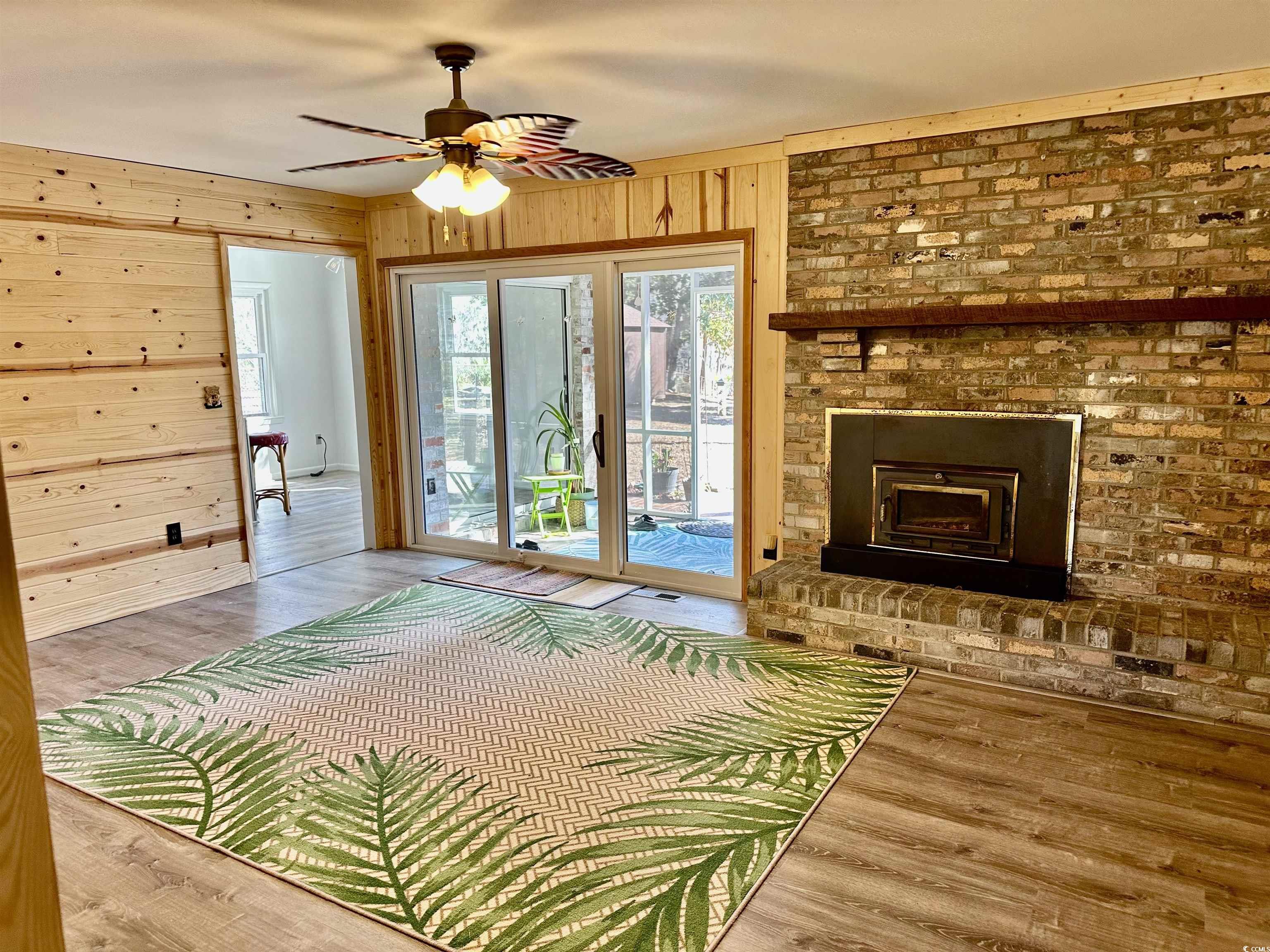 68 Mallard Circle Georgetown, SC 29440 - Photo 12 of 24 Unfurnished bedroom featuring access to exterior, wood finished floors, wood walls, ceiling fan, and a brick fireplace