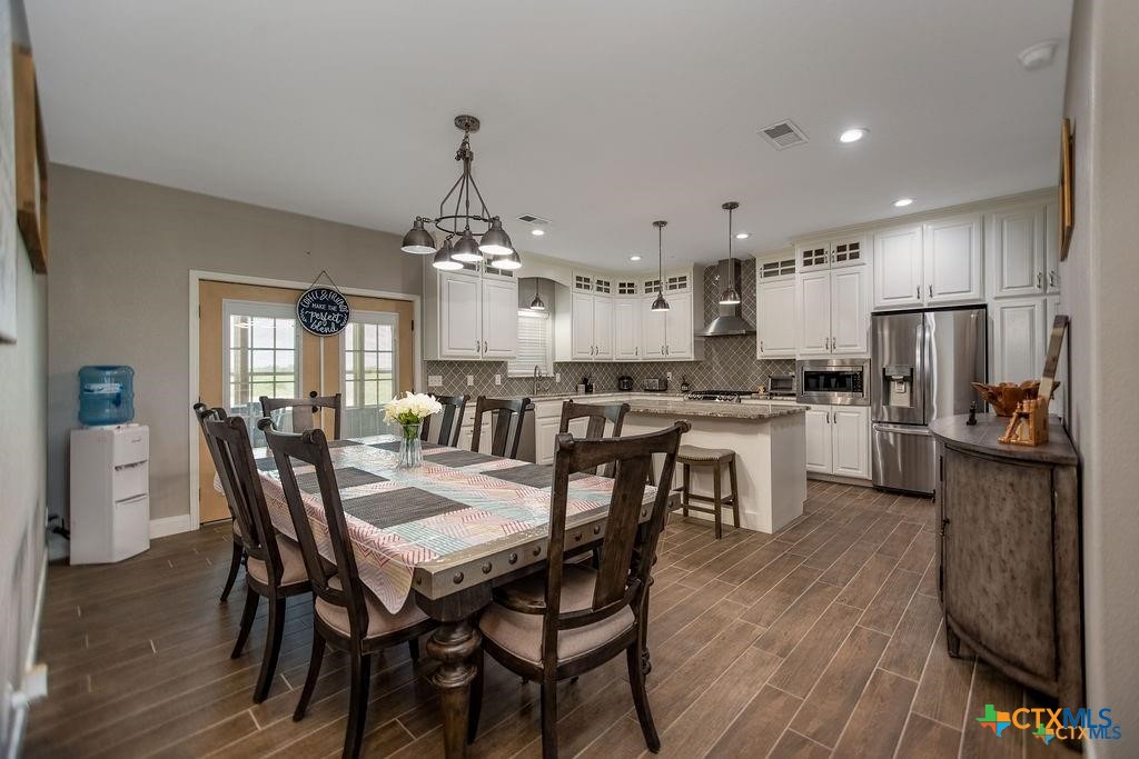 802 Mc Donald Road Port Lavaca, TX 77979 - Photo 14 of 45 a kitchen with a dining table chairs refrigerator and cabinets
