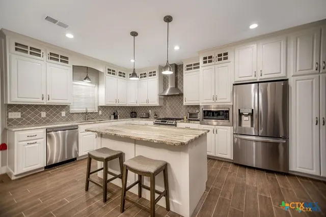 a kitchen with stainless steel appliances granite countertop a sink a stove and a refrigerator