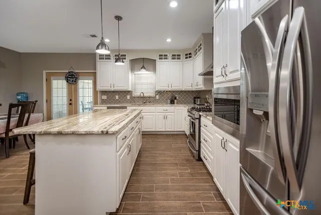 a kitchen with stainless steel appliances granite countertop a stove a sink and a refrigerator