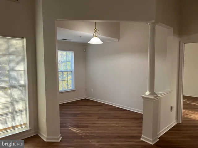 an empty room with wooden floor chandelier and windows
