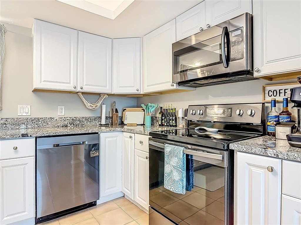 4748 Dixie Drive Ponce Inlet, FL 32127 - Photo 17 of 53 a kitchen with stainless steel appliances granite countertop a stove top oven microwave and cabinets