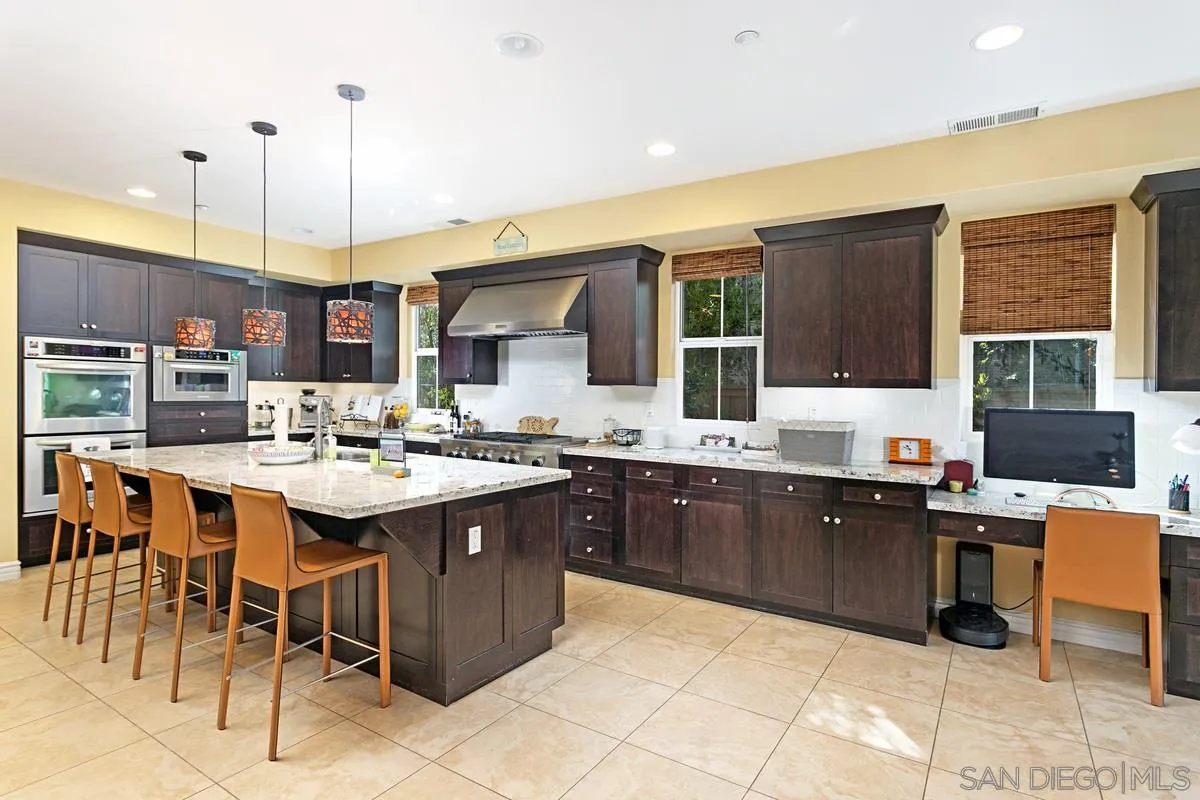 a kitchen with kitchen island granite countertop a sink counter top space appliances and a window