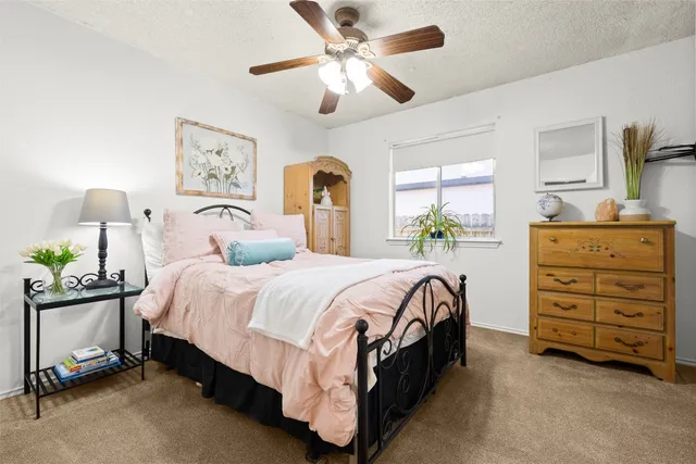 a spacious bedroom with a bed a dresser and a chandelier