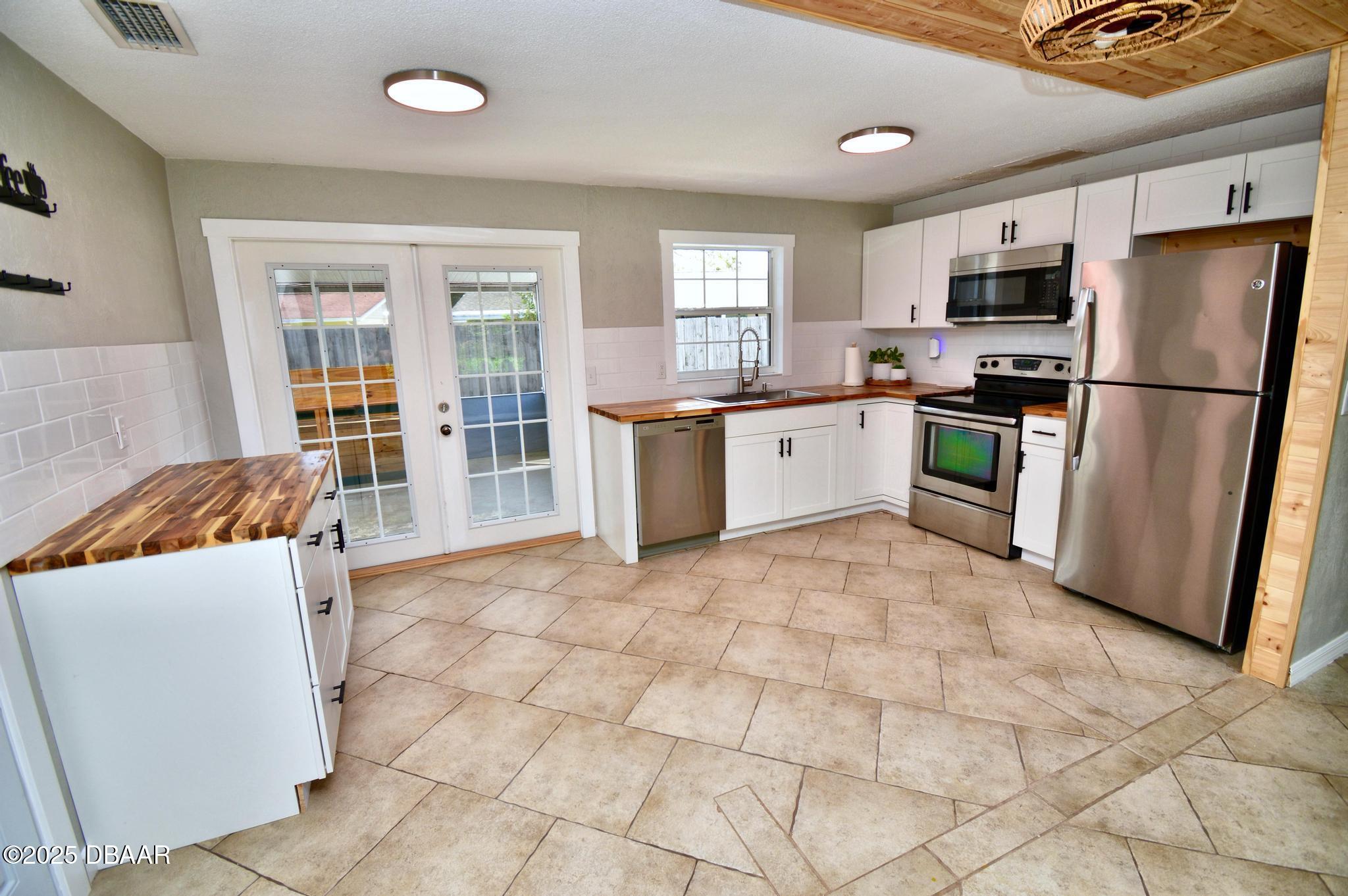 1025 2nd Street Port Orange, FL 32129 - Photo 18 of 33 a large kitchen with a stove a refrigerator a sink a microwave and a dining table