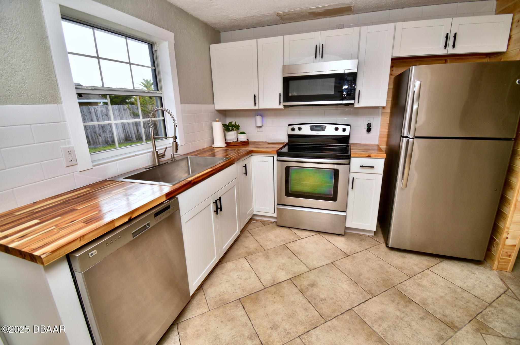 1025 2nd Street Port Orange, FL 32129 - Photo 22 of 33 a kitchen with granite countertop a refrigerator and a stove top oven