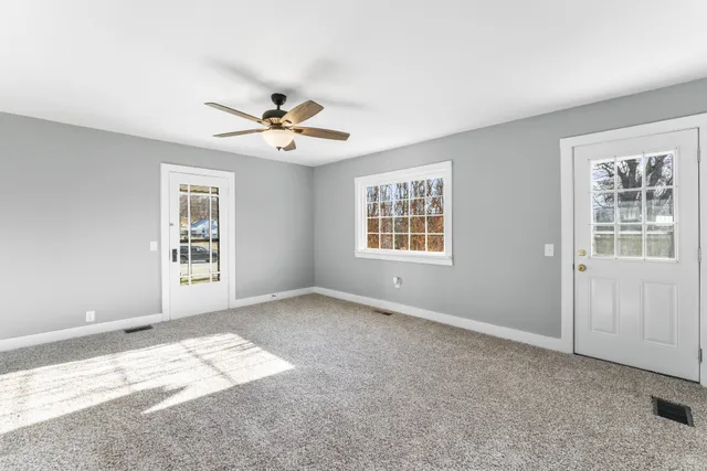 a view of an empty room with a chandelier fan and a window