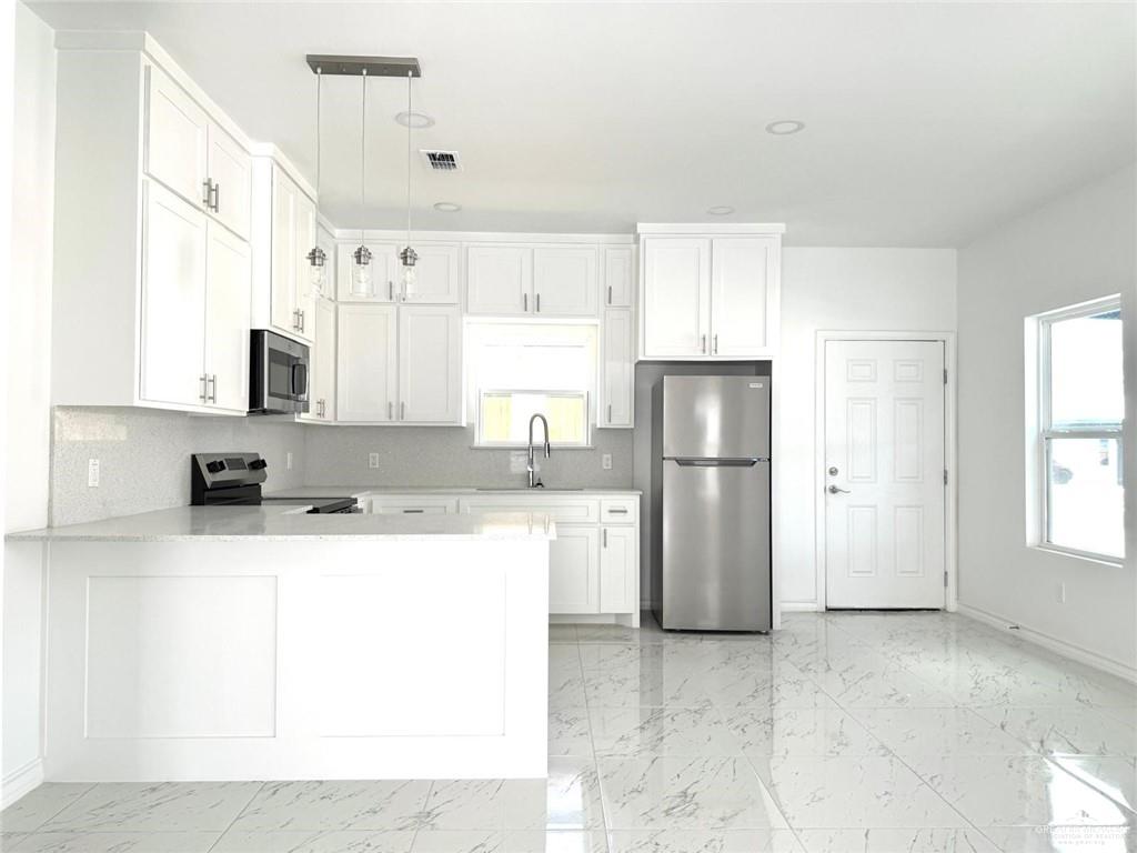 11308 North 25th Street, Unit 1 McAllen, TX 78504 - Photo 4 of 14 a kitchen with a sink a refrigerator and a stove